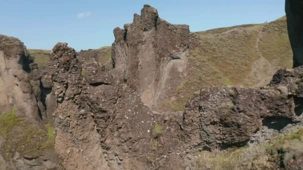Poletují podél rozeklaných stěn rokle ozářených jasným sluncem. Potok tekoucí po dně rokle. Fjadrargljufur canyon, Island — Stock video