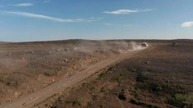 Toprak yolda giden araba yükselen toz. Güneşli bir günde Kuzey volkanik manzarasında rüzgarlı bir hava. İzlanda