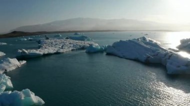 Romantik İskandinav manzarası. Gölde yüzen buzdağlarıyla korunmuş doğanın akşam görüntüsü. İzlanda