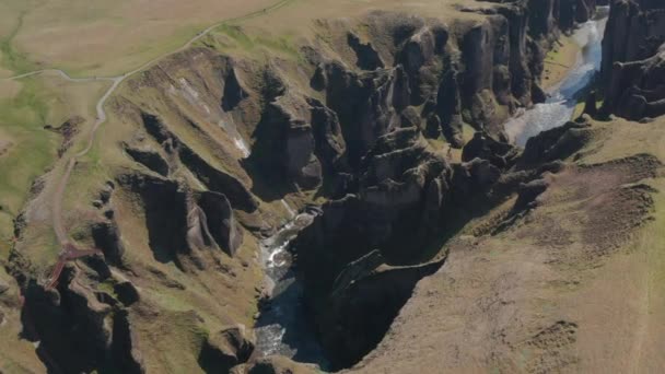 Vzdušný pohled na potok tekoucí v rokli. Vysokoúhlé záběry rozeklaných skalnatých stěn s bizarními tvary. Fjadrargljufur canyon, Island — Stock video