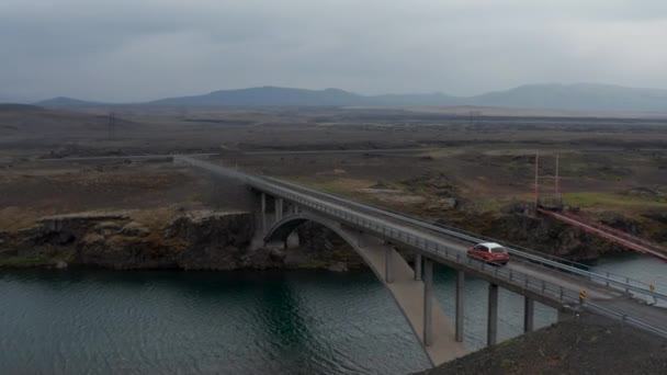 Luchtfoto van boogbrug over rivier. Auto rijden op de weg betonnen structuur overspannen water. Bewolkte dag in het Noordse landschap. IJsland — Stockvideo