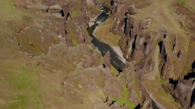 Havadan kesilen vadilerin panoramik görüntüleri. Engebeli kayalıklarla dolu vadiden akan su. Fjadrargljufur Kanyonu, İzlanda