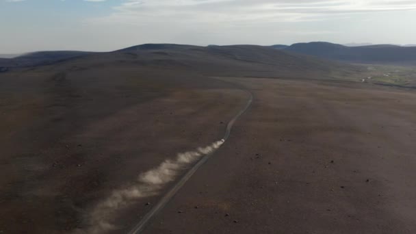 Images panoramiques aériennes du paysage nordique illuminé par le soleil. Voiture conduisant sur la route de terre et laissant des traces de poussière. Islande — Video