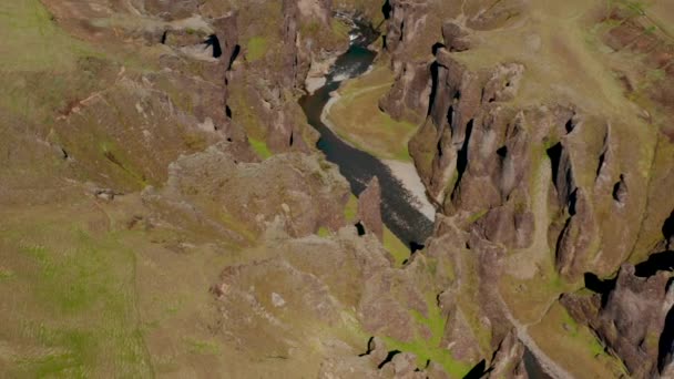Воздушные панорамные кадры оврага, вырубленного в землю. Вода течет через ущелье с прочными скалистыми скалами. Каньон Фьядлуфур, Исландия — стоковое видео