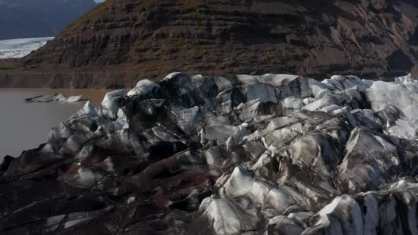 Leć nad końcem lodowca w dolinie. Brudny postrzępiony lód pokryty pyłem wulkanicznym. Górski krajobraz. Islandia — Wideo stockowe