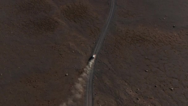Vysokoúhlé záběry rychle se pohybujícího auta na prašné polní cestě v sopečné pustině. Vycházející oblaka prachu. Island — Stock video