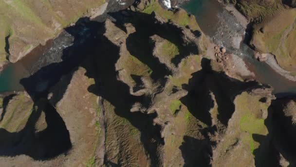 Aves aéreas olho em cima de cima para baixo vista de riacho fluindo através de garganta profunda e estreita cercada por várias rochas em forma. Fjadrargljufur canyon, Islândia — Vídeo de Stock