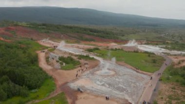 Jeotermal Geysirs 'in etrafında yürüyen ya da ayakta duran ziyaretçilerin hava görüntüsü. Sıcak jeotermal yaylar doğada. İzlanda
