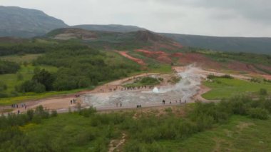 Aktif Geysir 'in hava panoramik görüntüleri. İnsanlar kaynayan suyun yükselişini izliyor. İzlanda