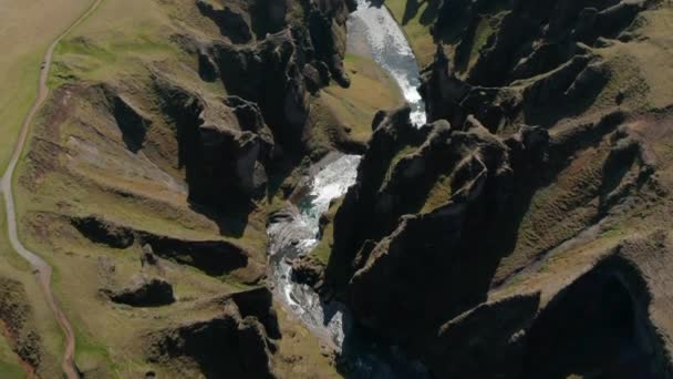 Vysoký úhel pohledu na třpytící se vodní hladinu potoka, tekoucí roklinou. Neobvyklé bizarní tvary skalních stěn. Fjadrargljufur canyon, Island — Stock video