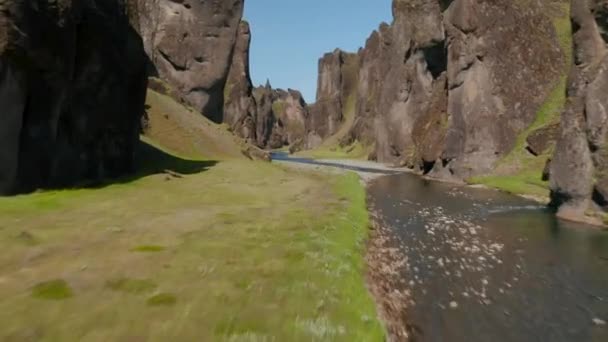 水面上的低空飞行。小溪平静地从狭窄的峡谷中流出.岩石墙壁被阳光照亮了.令人惊奇的自然保护。Fjadrargljufur峡谷，冰岛 — 图库视频影像