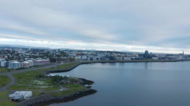 Şehrin panoramik görüntülerinde artış var. Sahile çıkan yol ve kentsel çevredeki çeşitli binalar. Sakin su yüzeyi.