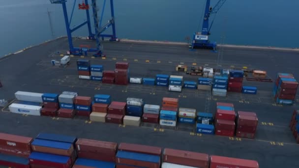 Vola sopra file su container di trasporto in terminal in porto. Tilt up rivelano di superficie dell'acqua e montagne in lontananza. — Video Stock
