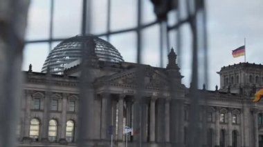 Deutscher Bundestag binasının orta kısmı çelik ve cam kubbeli. Alman, İsrail ve AB bayrakları Alman parlamentosu önünde. Berlin, Almanya