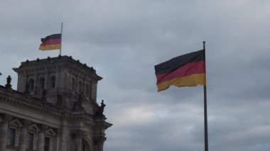 Rüzgarda sallanan Alman bayrakları. Tarihi Deutscher Bundestag binasında ulusal tema. Bulutlu bir gün. Berlin, Almanya