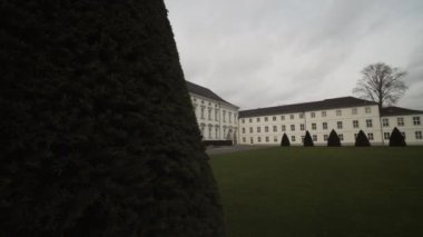 Bellevue Sarayı 'nı ortaya çıkarmak. Başkanlık konutu olarak kullanılan tarihi bina. Ana girişin önünde yeşil çim ve kozalaklı ağaçlar var. Berlin, Almanya
