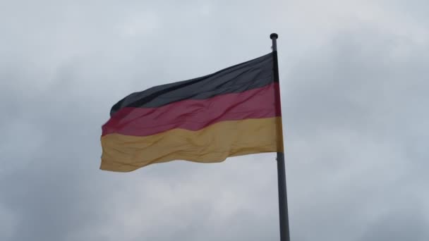 Siyah, kırmızı ve altın rengi. Alman ulusal bayrağını kapatın bulutlu gökyüzüne karşı rüzgarda dalgalanan kutupta. — Stok video