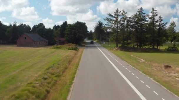前路飞驰而上，骑自行车的人带着树木和房屋穿过乡村。开车在路上。丹麦 — 图库视频影像