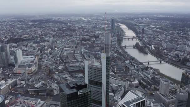 Aerial descending view of Commerzbank Tower and cityscape. Several bridges spanning river winding through town. Frankfurt am Main, Germany — Stock Video