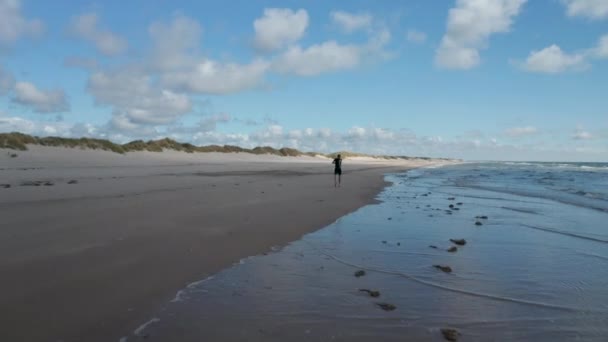 Sporing av mennesker som jogger på kysten. Sportsmann som løper på stranden langs milde bølger. Danmark – stockvideo