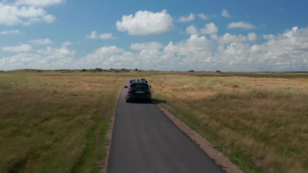 Rodzinny samochód na wąskiej drodze na wsi. Łąki i pastwiska z wysoką trawą wzdłuż drogi. Dania — Wideo stockowe