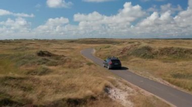 Düz kırsalda dar bir yolda giden arabanın izini sürüyorum. Yaklaşan bisikletçilere yaklaşıyoruz. Danimarka