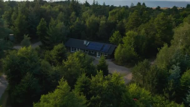 木の間の家やコテージの高い角度のビュー。傾きは海の海岸と水面を明らかにします。デンマーク — ストック動画