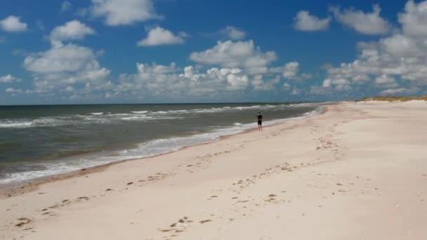 Csodálatos felvétel a tengerparti tájról. A homokos parton futó férfi nyomára bukkantunk a napsütéses napon. A nyári vakáció helyszíne. Dánia — Stock videók