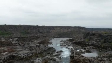 İnsansız hava aracı Skjalfandafljot nehrinde kaya ve bazalt oluşumlarıyla süzülüyor. İzlanda dağlarının kuzey kesimindeki Aldeyjarfoss şelalesinin hava manzarası