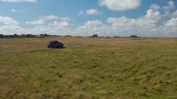 田舎の狭い道を車の運転の追跡。いくつかの建物と広大な平らな草原。デンマーク — ストック動画