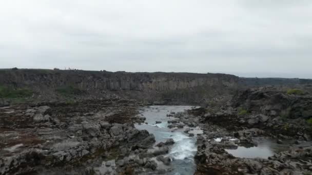 Drone view flying through water flowing on river of Skjalfandafljot with rock and basalt formations. Aerial view of Aldeyjarfoss waterfall situated in the northern part of icelandic highlands — Stock Video