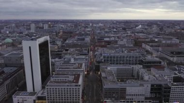 Alacakaranlıkta büyük bir kasabada uzun düz bir caddenin havadan görüntüsü. İleri, Friedrichstrasse 'nin üzerinden uçarak şehir mahallelerinden geçiyor. Berlin, Almanya
