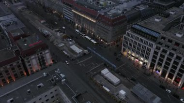 Geniş bulvarın ortasındaki inşaat sahasının hava görüntüleri yükseliyor. Alacakaranlıkta alışveriş caddesi. Berlin, Almanya