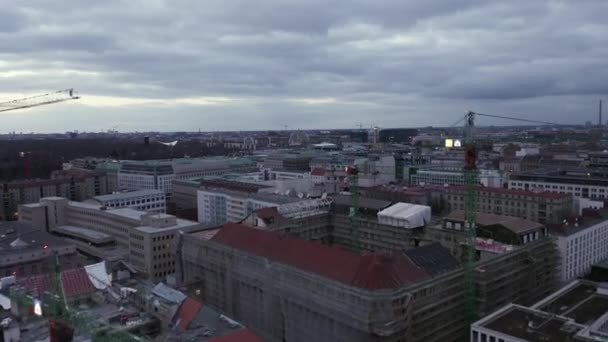Survolez des grues à tour sur un chantier de construction dans un quartier urbain. Bâtiments en ville au crépuscule. Berlin, Allemagne — Video