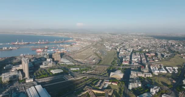 Légi felvétel a közlekedési infrastruktúráról a nagyvárosban. Kilátás a nagy tengerentúli kikötő, vasútállomás kiterjedt vasúti sínek és forgalmas főutak. Fokváros, Dél-Afrika — Stock videók