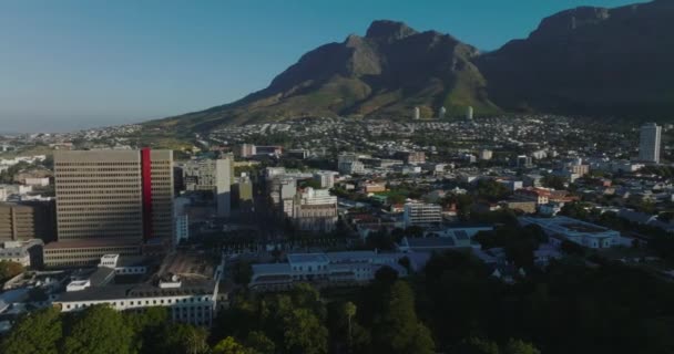 Şehirdeki binaların hava görüntüleri. Arka planda kayalık dağ zirveleri var. Güneşli bir günde gökyüzü açık. Cape Town, Güney Afrika — Stok video