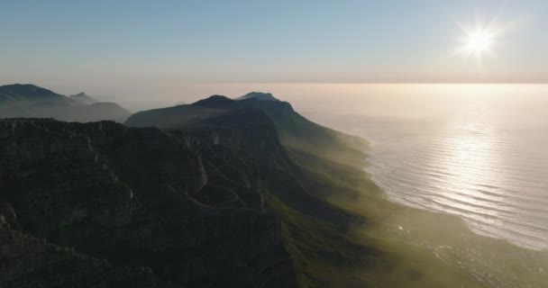 Luftaufnahmen von Küstenlandschaften. Hohe zerklüftete Felskämme über der Meeresküste gegen untergehende Sonne. Kapstadt, Südafrika — Stockvideo