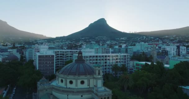 前方の都市のアパートの建物の上に飛ぶ。ライオンズ明るい太陽をカバーする町の上の頭の山。南アフリカ共和国ケープタウン — ストック動画