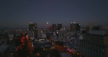 Gece şehir merkezinin yükselişi. Aydınlanmış sokaklar ve yüksek binalar. Liman limanıyla denize açılıyor. Cape Town, Güney Afrika