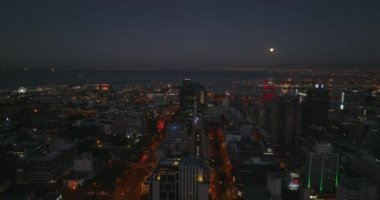 İleri, şehir merkezindeki yüksek binaların üzerinde uçuyor. Deniz koyunda geceleri büyük bir liman var. Cape Town, Güney Afrika