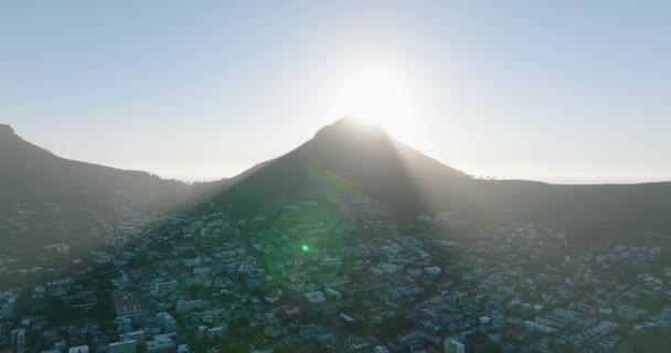 Aerial descending shot of Lions Head mountain casting shadow residential borough. View against sun. Cape Town, South Africa — Stock Video