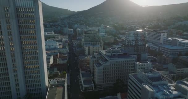 Vue panoramique du développement de la ville. Inclinez-vous pour révéler la montagne de Lions Head qui jette de l'ombre sur les bâtiments du quartier urbain. Cape Town, Afrique du Sud — Video