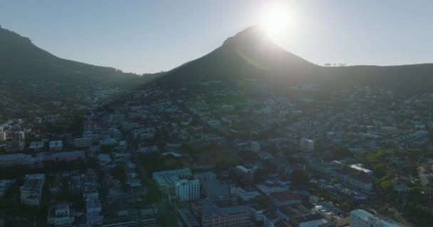 Adelante vuelan por encima de los edificios residenciales en los suburbios. Leones Cabeza montaña contra el sol. Ciudad del Cabo, Sudáfrica — Vídeo de stock