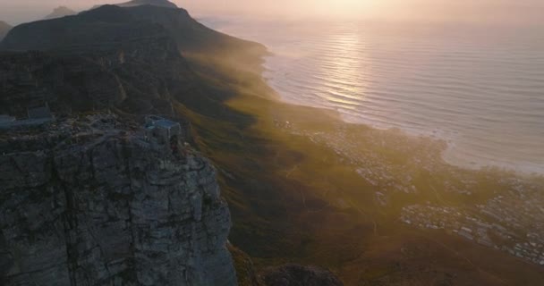 Adembenemend landschap luchtfoto landschap. Vlieg over de top van de Tafelberg, panoramisch uitzicht op de rotsrug en de oceaankust tegen de pittoreske zonsondergang. Kaapstad, Zuid-Afrika — Stockvideo