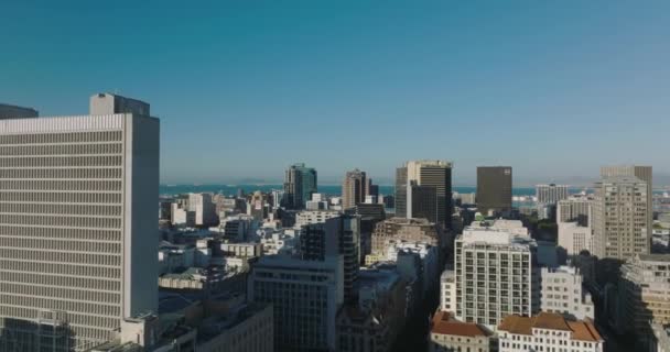 Voorwaarts vliegen boven kantoor- of woongebouwen in de stad verlicht door de felle zon. Vrachtschepen op zee op afstand. Heldere blauwe lucht. Kaapstad, Zuid-Afrika — Stockvideo