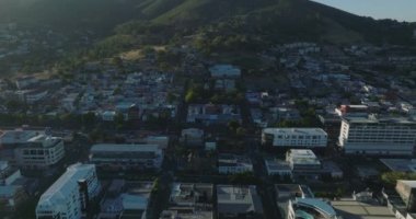 Forvetler şehir mahallelerinin üzerinde uçar. Şehrin varoşlarında, yamaçtaki iskan evleri. Ana yol çok yoğun. Cape Town, Güney Afrika