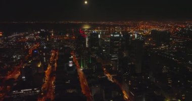 Geceleri şehrin üstünde uç. Renkli caddeler ve şehir merkezindeki yüksek ofis binaları. Arka planda Masa Koyu 'ndaki liman. Cape Town, Güney Afrika