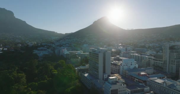 Desenvolvimento da cidade e Lions Head montanha contra o sol brilhante. Avante voar acima de edifícios em City Bowl. Cidade do Cabo, África do Sul — Vídeo de Stock