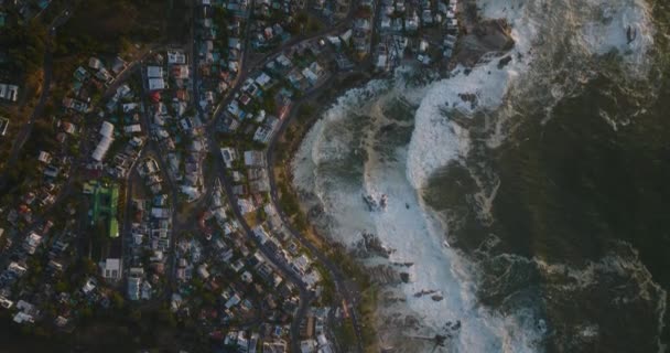 Havadan kuşların gözü deniz kıyısında dalgaların akışını yukarıdan görüyor. Sahil boyunca yerleşim yerlerindeki binalar. Cape Town, Güney Afrika — Stok video