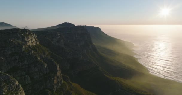 Avanti volare lungo cresta rocciosa sopra la costa del mare. Paesaggio stupefacente scenario contro il sole luminoso al tramonto. Città del Capo, Sud Africa — Video Stock
